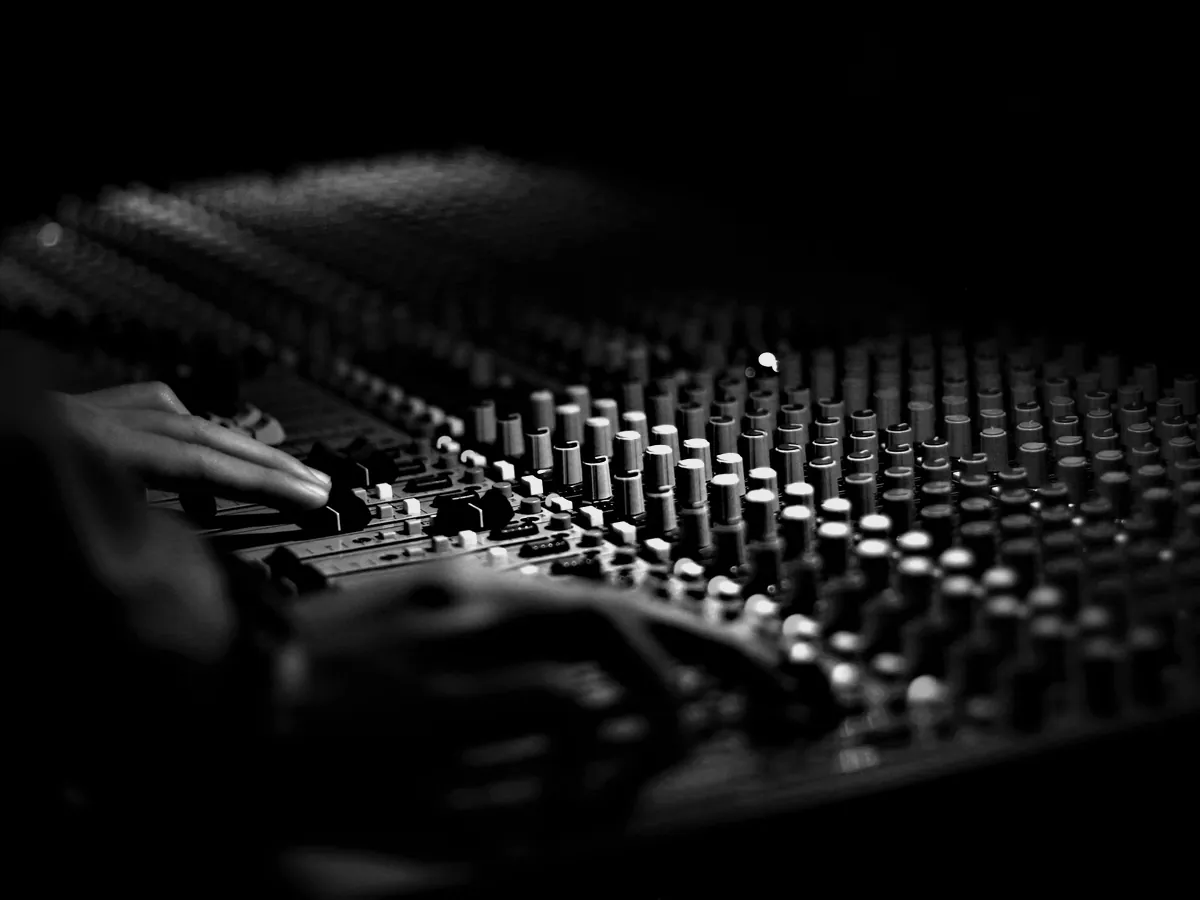 Hands on the faders of a mixing desk