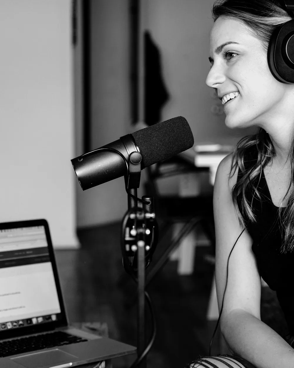 A podcaster with headphones on, recording at a desk microphone